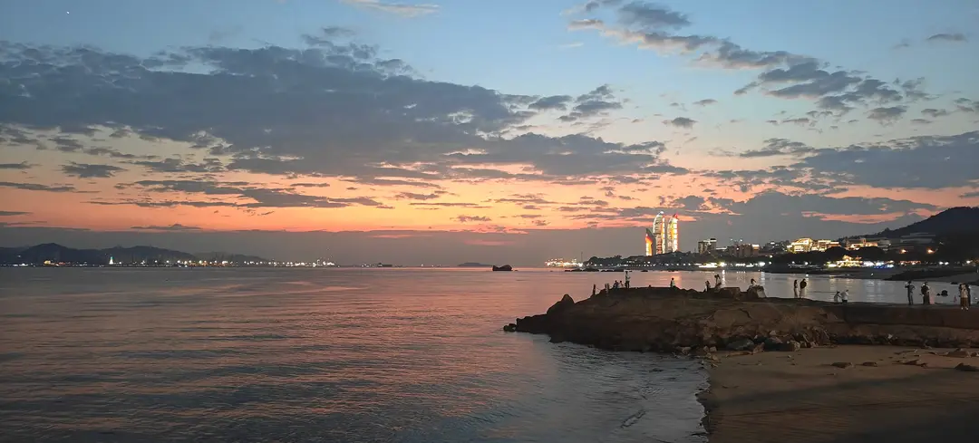 Dusk on the Xiamen shore, the twin towers lighting up across the bay